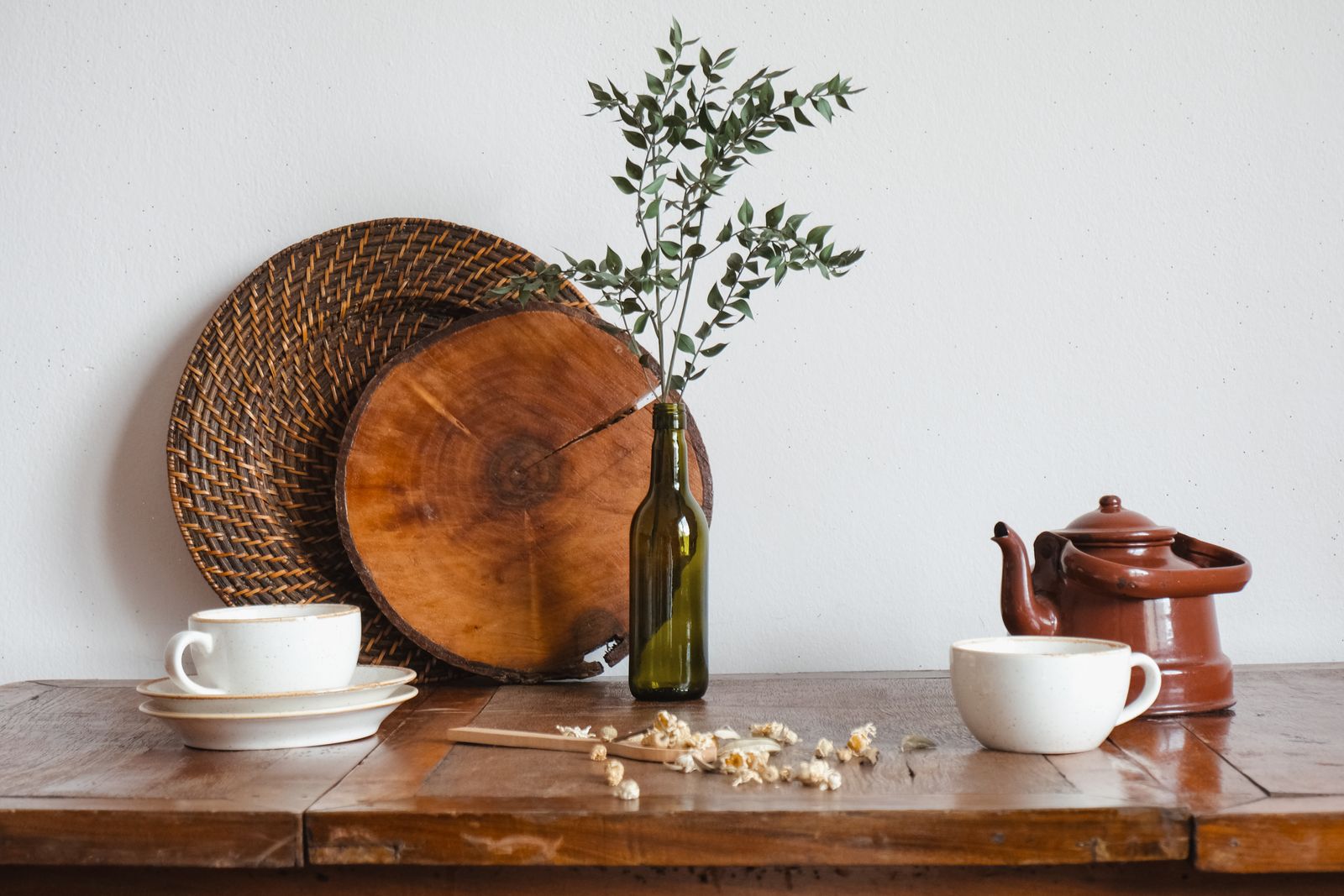 Ceramic cups and greenery arranged on a wooden table